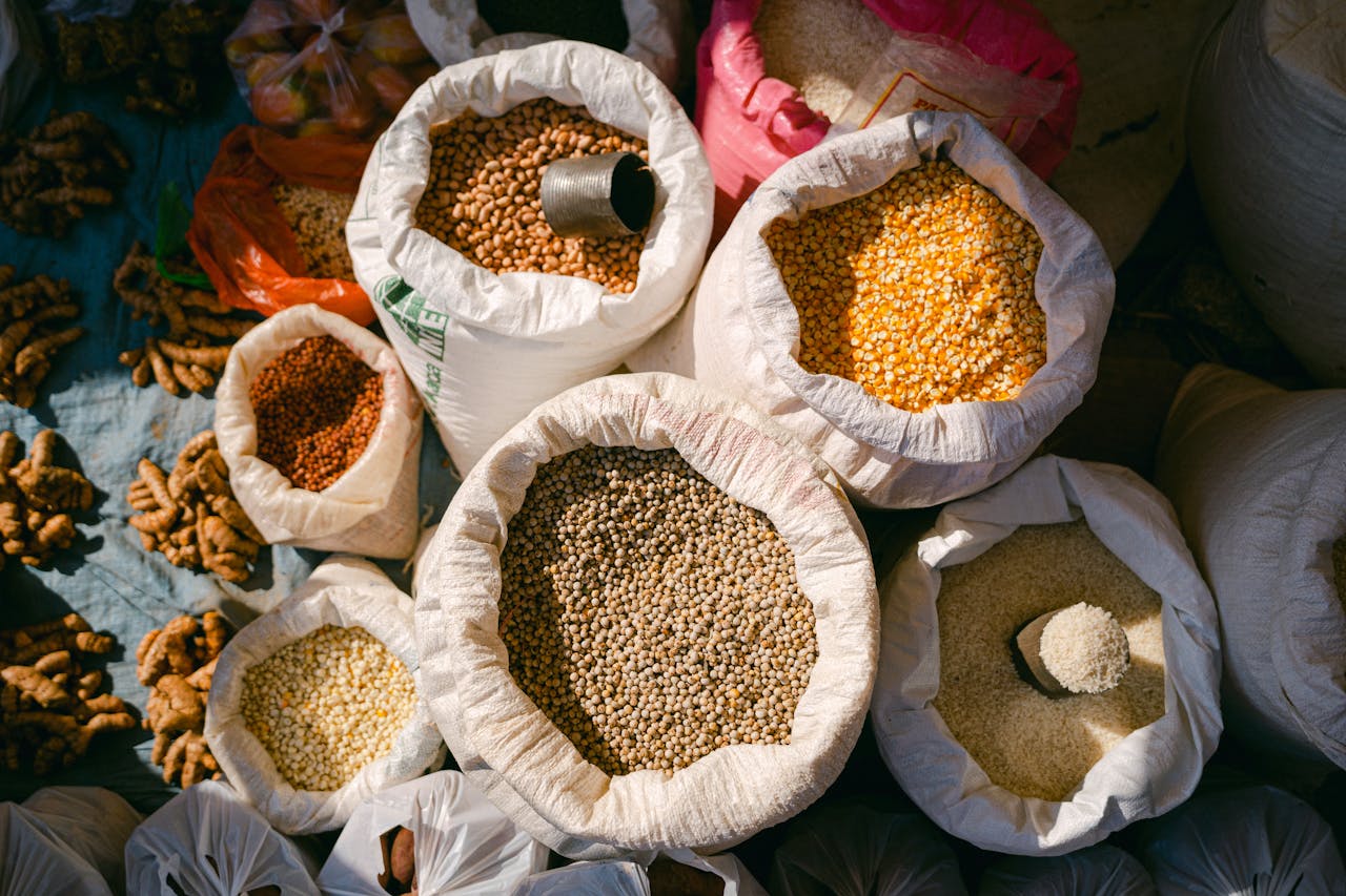 Overhead shot of grains and spices in sacks at an outdoor market, capturing diverse textures and colors.