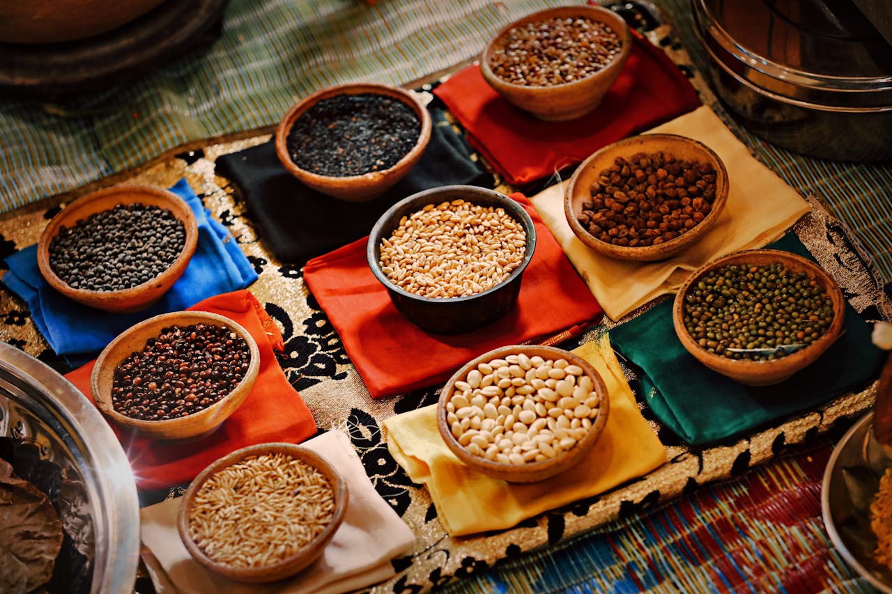 A vibrant assortment of grains and beans in ceramic bowls arranged on colorful textiles, showcasing diverse ingredients.